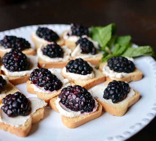 a white plate topped with mini sandwiches covered in blackberries