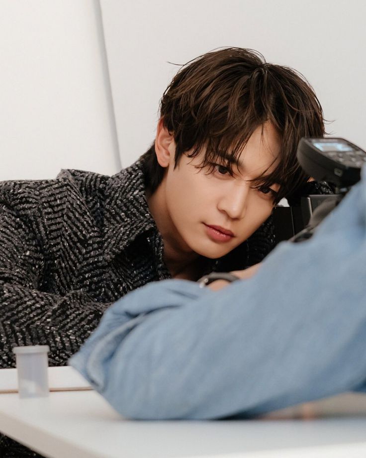 a young man sitting at a table holding a cell phone