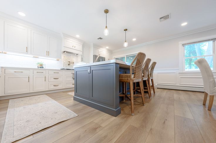 a large kitchen with white cabinets and wooden flooring, along with a dining room table