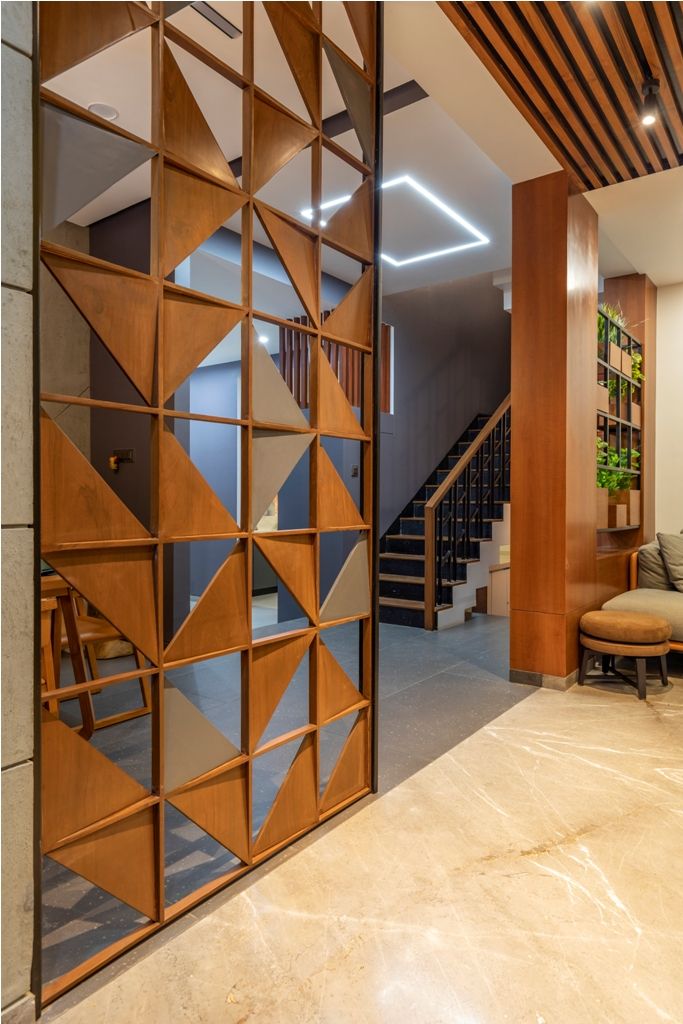 an open wooden door leading to a living room with stairs in the back ground and a couch on the other side