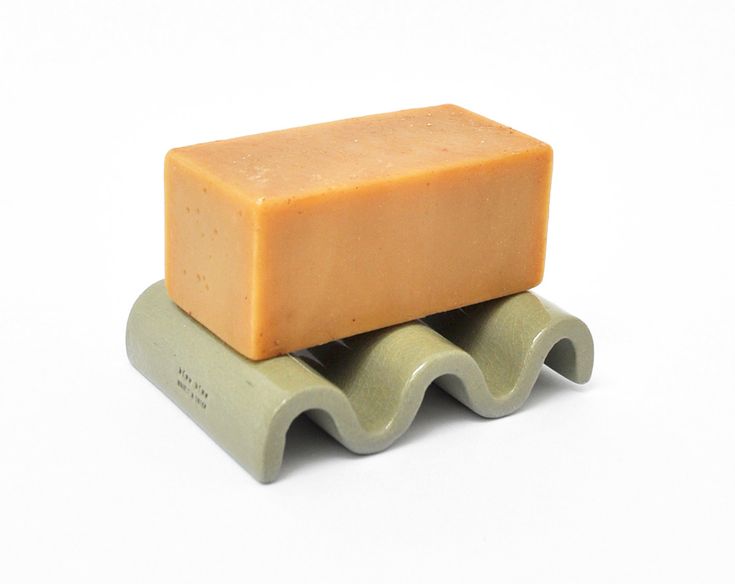 a bar of soap sitting on top of two green rollers against a white background