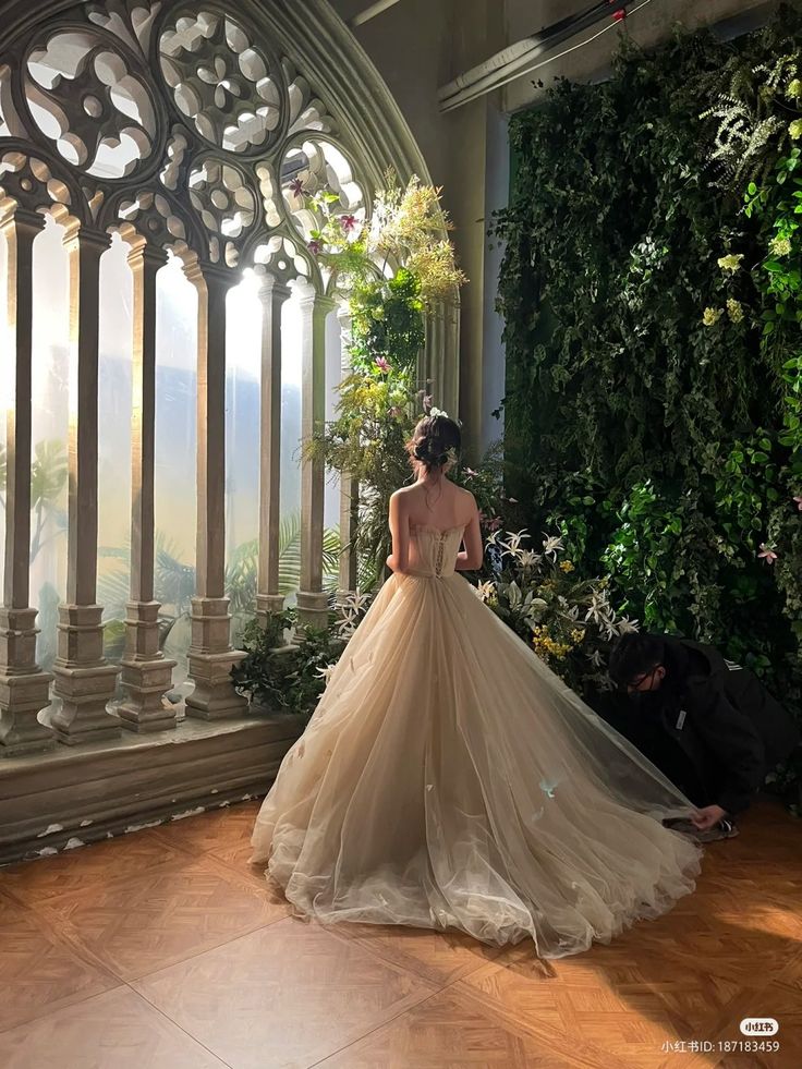 a woman in a wedding dress is looking out the window