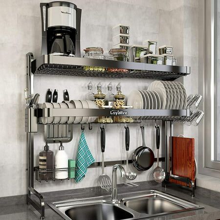 a stainless steel kitchen sink and shelf filled with utensils