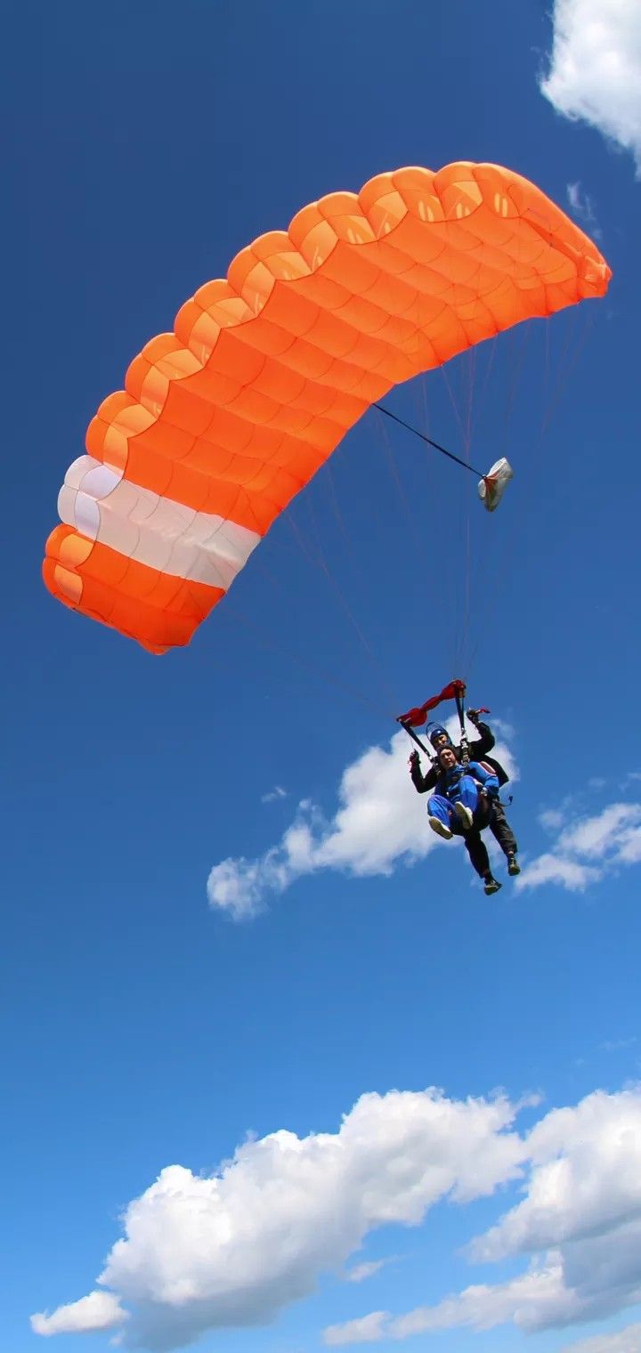 two people are parasailing in the blue sky