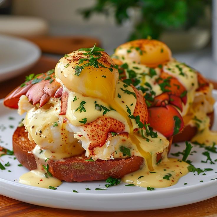 a white plate topped with two lobster sandwiches covered in hollandaise and mayonnaise