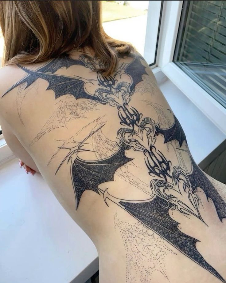 the back of a woman's body with tattoos on it