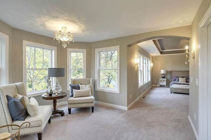 a living room filled with furniture and two windows next to each other on top of a carpeted floor