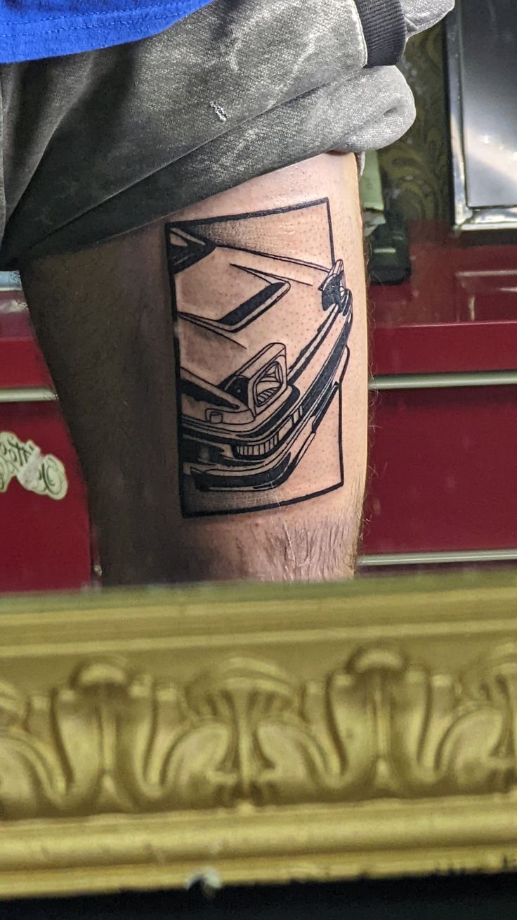 a man's leg with a car tattoo on it in front of a mirror