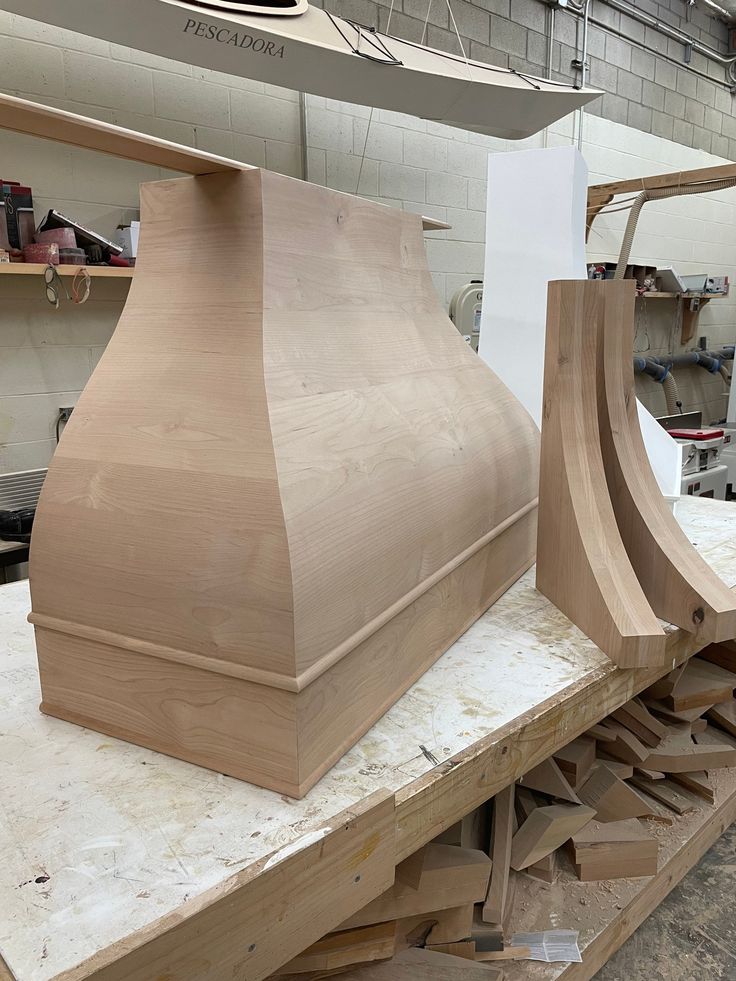 a wooden stove hood sitting on top of a workbench in a shop or workshop