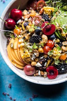 a white bowl filled with fruit and nuts on top of a blue table next to two forks