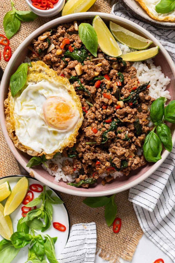 a bowl filled with rice, meat and vegetables next to some sliced lemon wedges