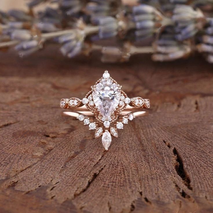 a close up of a ring on a piece of wood with flowers in the background