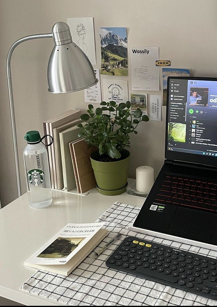 a laptop computer sitting on top of a white desk next to a lamp and books