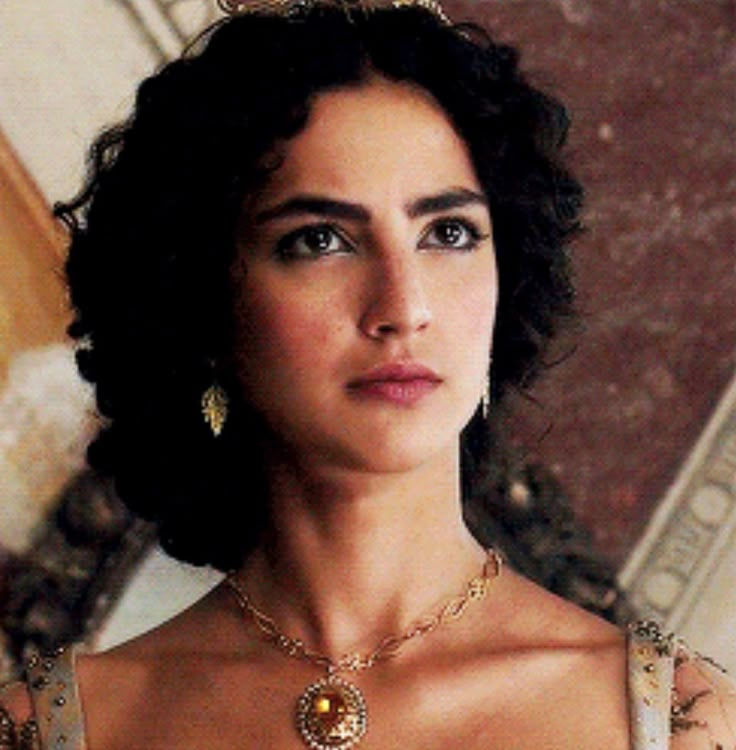 a woman in a white dress wearing a gold necklace and earring with an ornate design on it