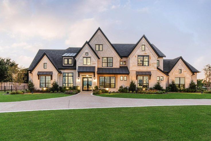 a large house with lots of windows on the front and side of it, surrounded by lush green grass