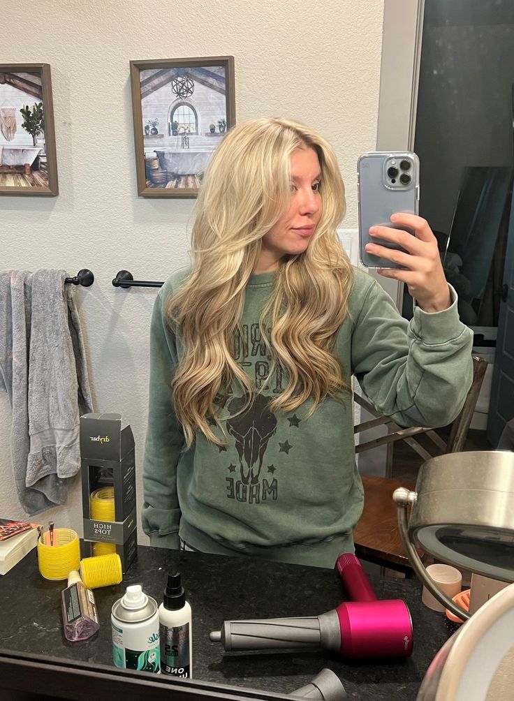 a woman taking a selfie in front of a mirror with her hair dryer