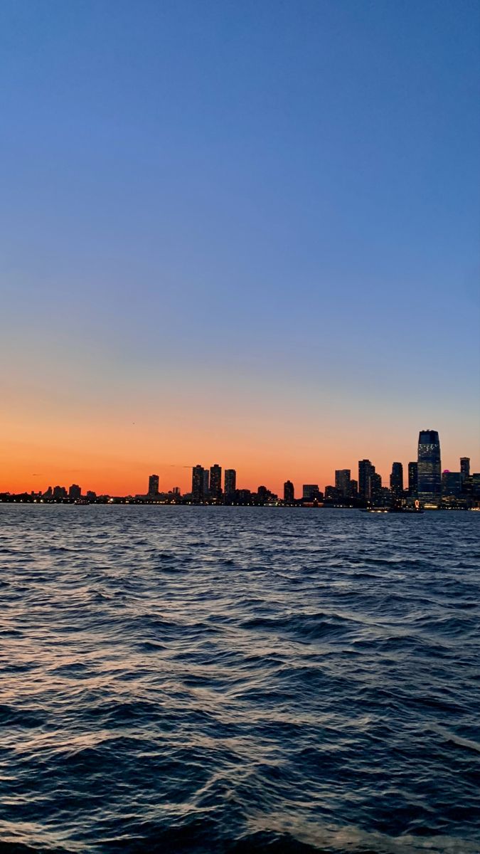 the city skyline is seen from across the water at sunset