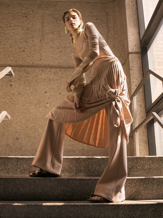 a woman standing on some steps with her hands in her pockets