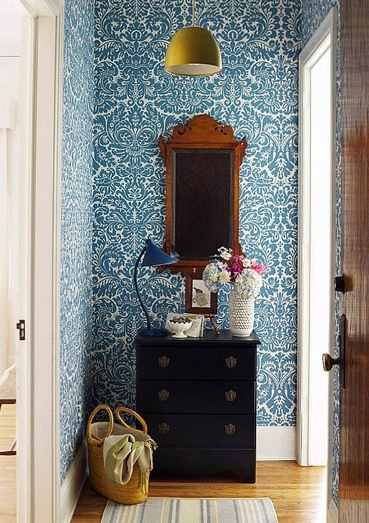 a room with blue wallpaper and a mirror on the dresser in front of it