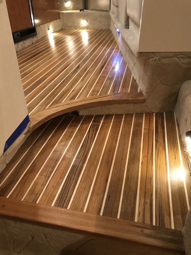 a wooden deck with lights on it and some steps leading up to the top floor