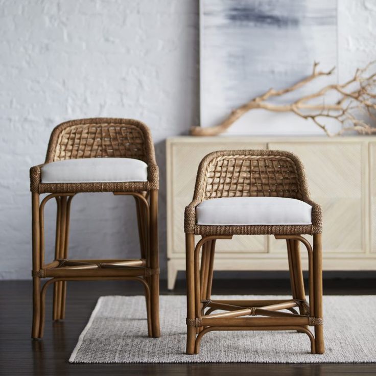 two wicker bar stools sitting on top of a rug next to a dresser