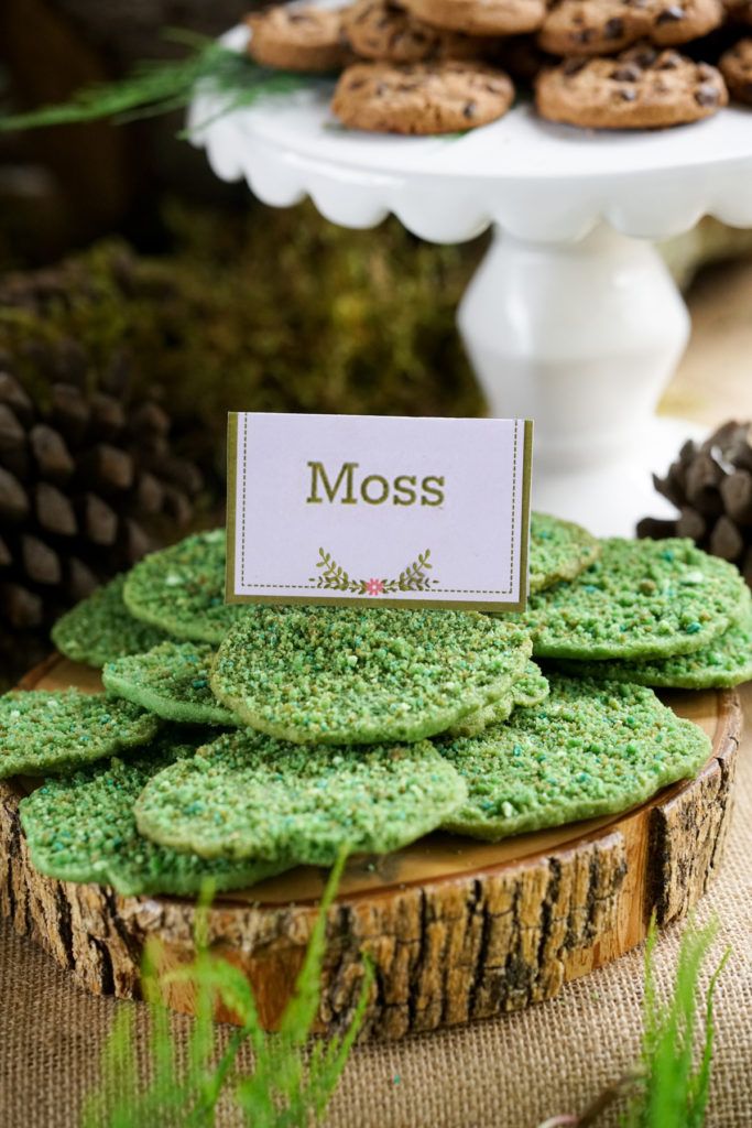 cookies are stacked on top of each other in front of a cake plate and pine cones