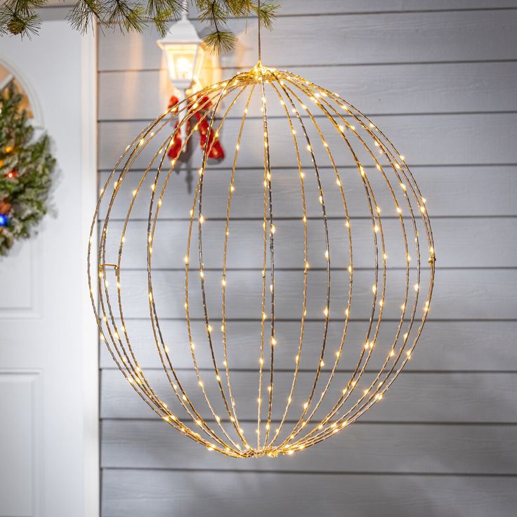 a christmas ornament hanging from the side of a house with lights on it