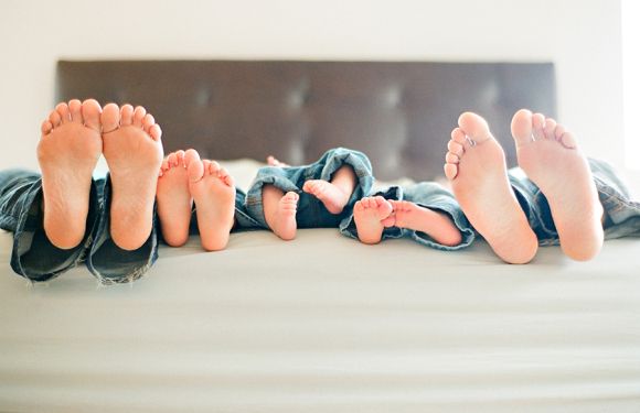 three people laying on top of a bed with their feet hanging over the edge of the bed