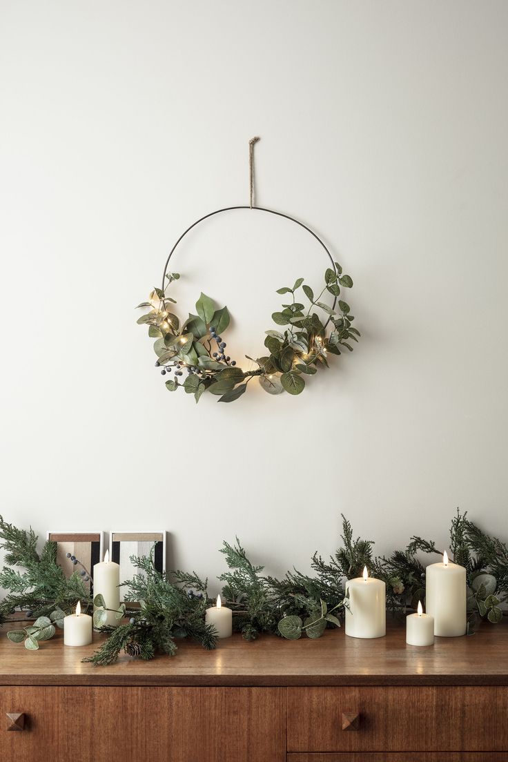 candles and greenery are arranged on a dresser