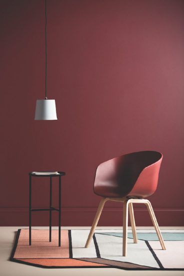 a red chair sitting on top of a white floor next to a table with a lamp