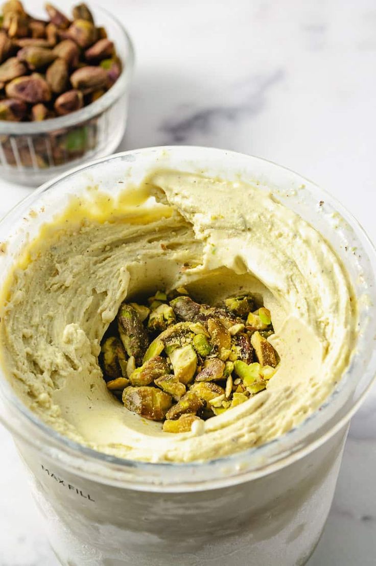 a bowl filled with hummus and nuts on top of a table