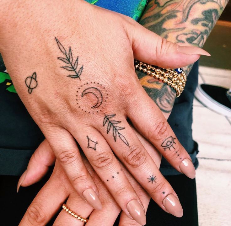 two people with tattoos on their hands holding each other's fingers and looking at the camera