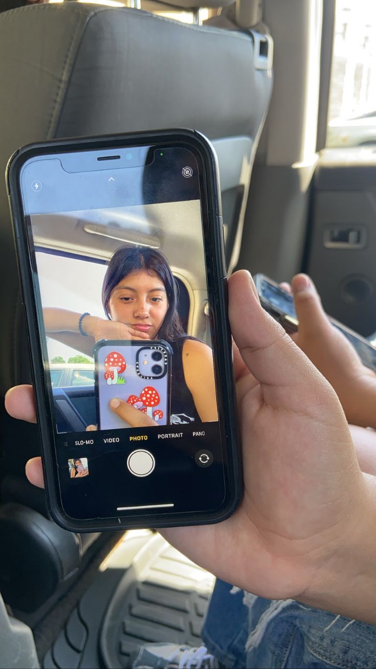 a person holding up a cell phone with a photo on it in the back seat