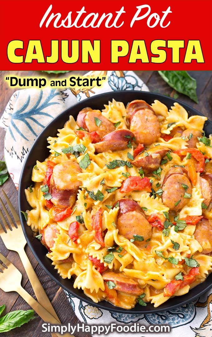 pasta with sausage and tomatoes in a skillet on a napkin next to silverware