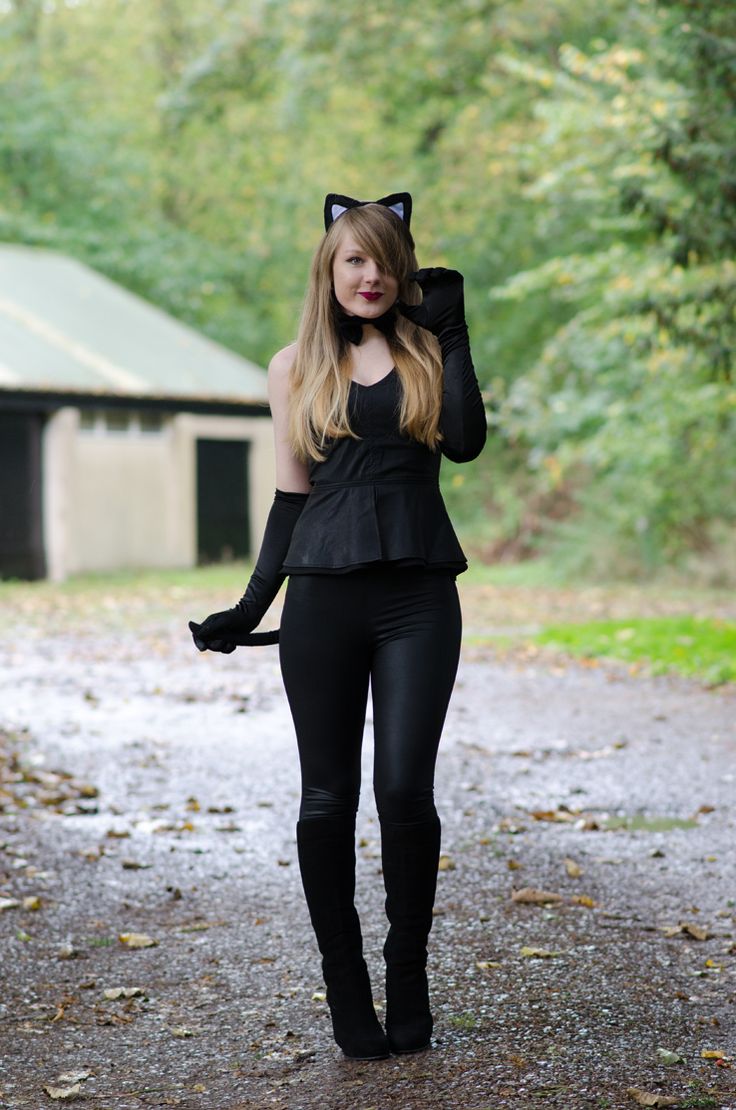 a woman in black catsuits walking down a dirt road