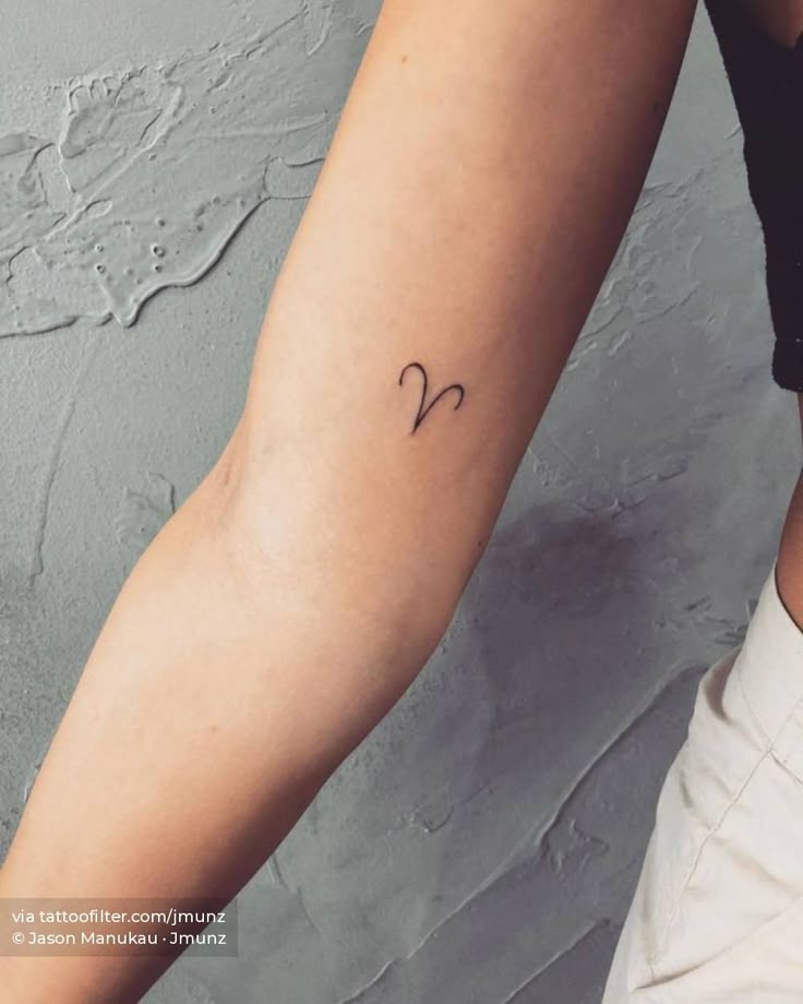 a woman's arm with a small heart tattoo on the left side of her right arm