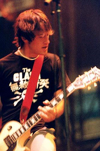 a young man playing an electric guitar on stage