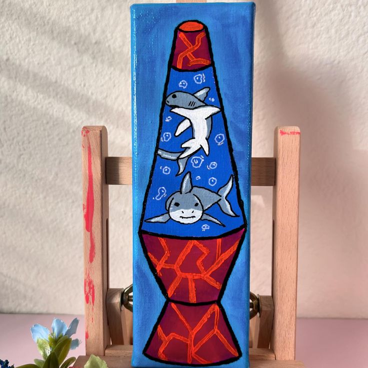 a painting of two dolphins on a blue bottle with red and orange ribbon around it