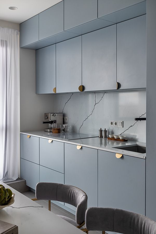 a kitchen with blue cabinets and marble counter tops, along with two chairs in front of the sink