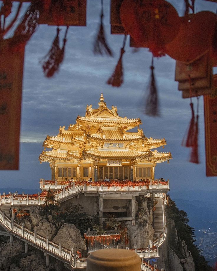 the golden building is on top of a mountain with many decorations hanging from it's sides