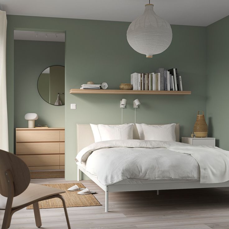 a bedroom with green walls, white bedding and wooden flooring is pictured in this image