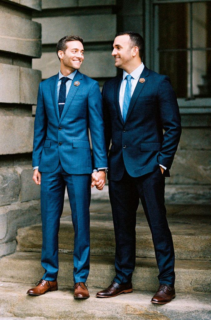 two men in suits standing next to each other on the steps outside an old building