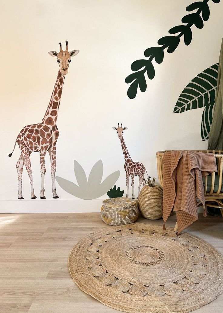 two giraffes standing next to each other in front of a wall mural