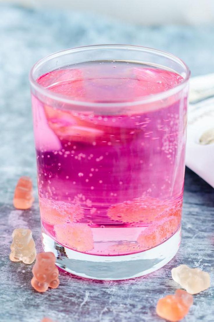 a glass filled with pink liquid and gummy bears