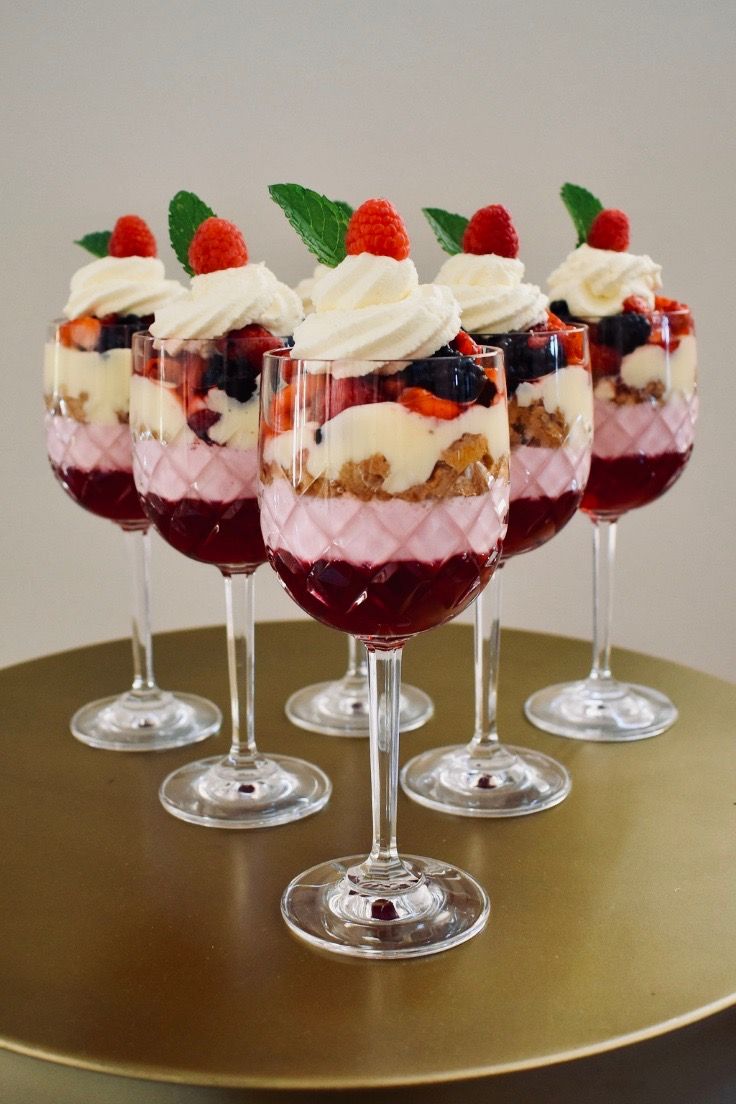 mini christmas trifles with berries and whipped cream in them on a table top