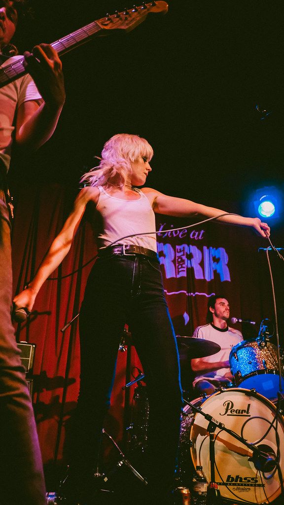 a woman standing on top of a stage next to a man holding an electric guitar