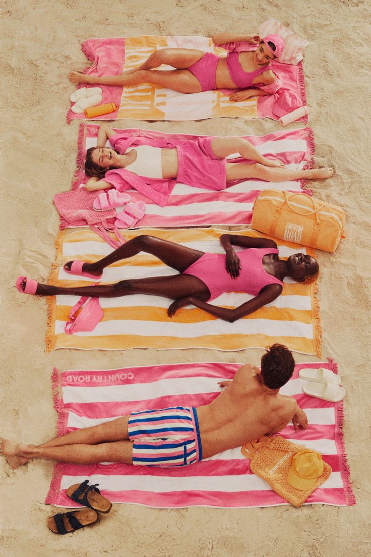 three people laying on towels at the beach