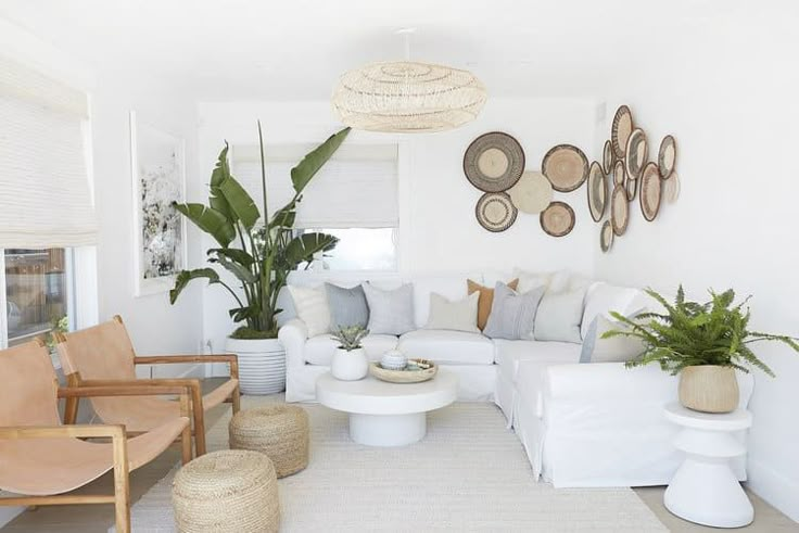 a living room filled with lots of white furniture and potted plants on the wall