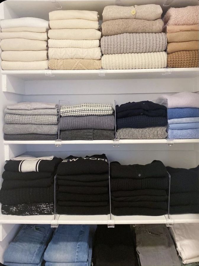 an organized closet with folded towels, sweaters and pants on shelving unit shelves