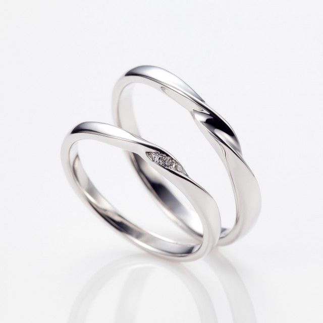 two white gold wedding rings with diamonds on top and one diamond in the middle, against a white background